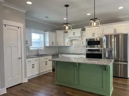 a kitchen with kitchen island granite countertop a sink refrigerator and microwave