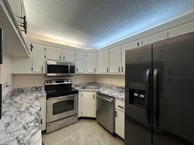 a kitchen with stainless steel appliances white cabinets and a refrigerator