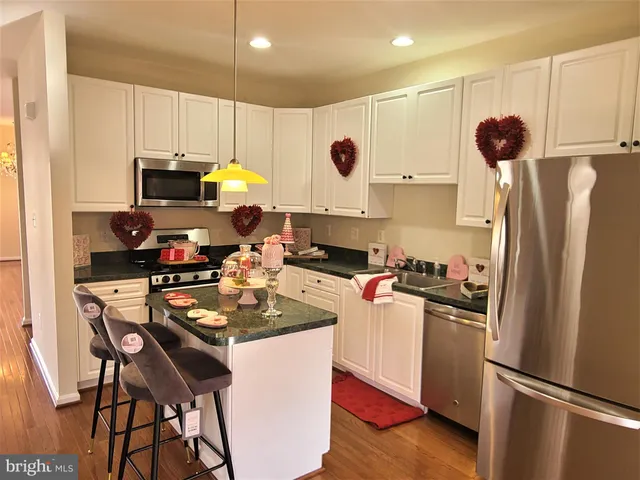 a kitchen with stainless steel appliances kitchen island granite countertop a refrigerator stove microwave and sink