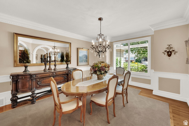 7740 Keswick Road Sandy, UT 84093 - Photo 11 of 74 Formal dining area featuring a crystal chandelier, crown molding, chair rail molding, a large picture window, and wood-finish flooring