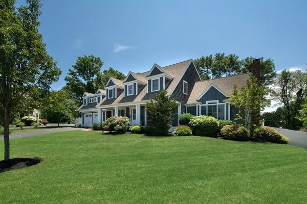 a front view of a house with a garden and trees
