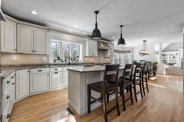 a kitchen with stainless steel appliances a dining table chairs sink and cabinets