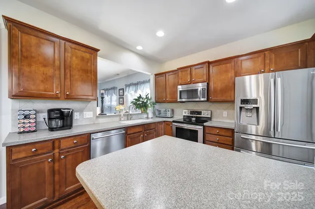a kitchen with stainless steel appliances granite countertop a refrigerator a stove top oven a sink and dishwasher