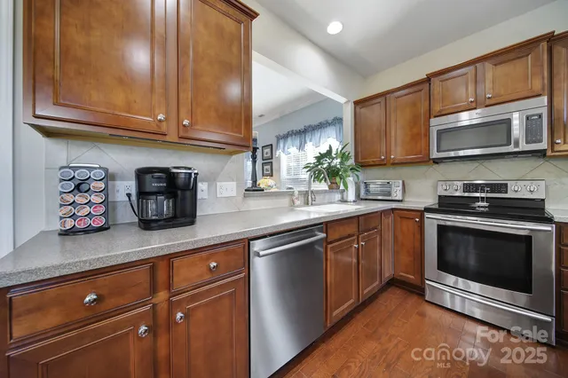 a kitchen with stainless steel appliances granite countertop a stove a sink and a microwave