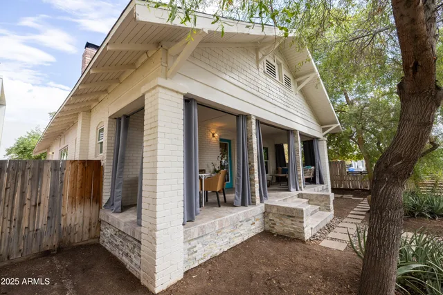 a view of a white house with a large tree