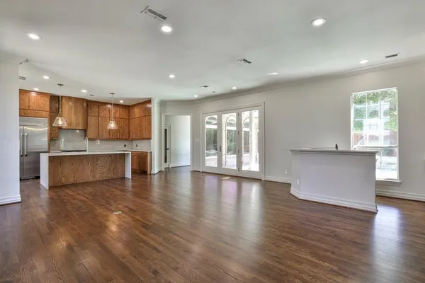 an empty room with wooden floor cabinet and windows