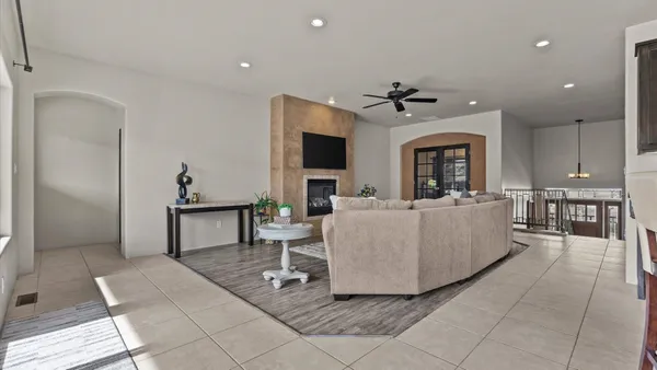 a living room with couches and a flat screen tv with kitchen view