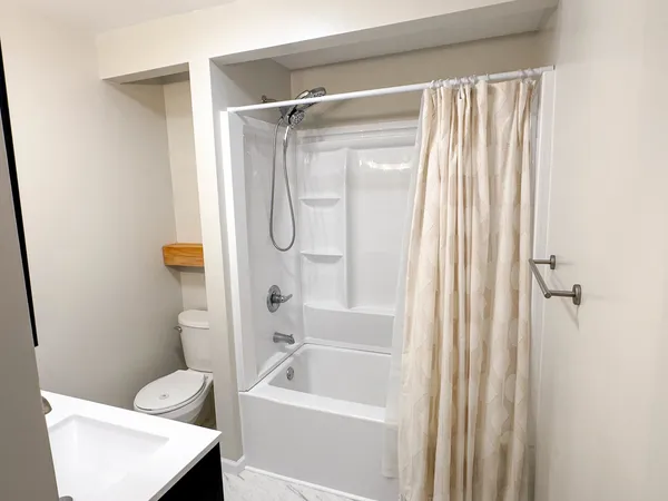 a bathroom with a granite countertop bathtub shower sink vanity and toilet