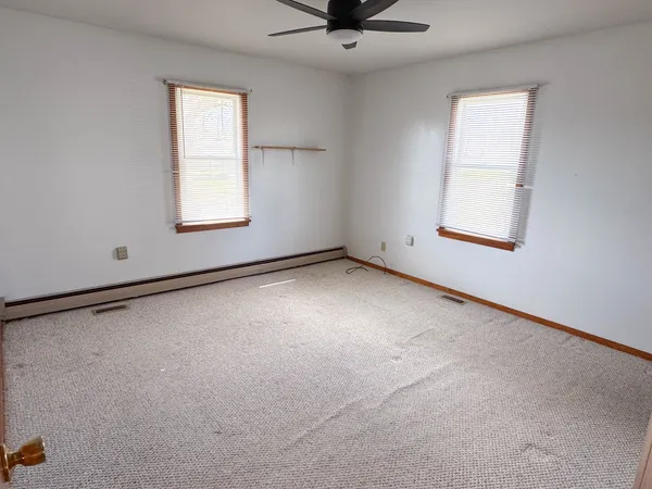 an empty room with a window and a fan