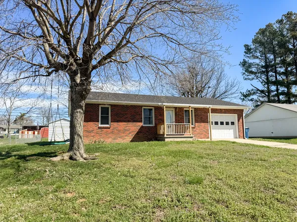 a front view of a house with a yard and trees