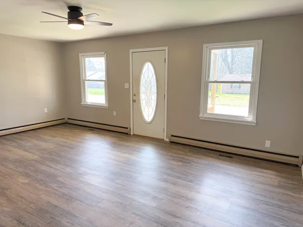 an empty room with wooden floor and windows
