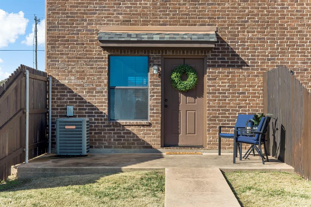 11118 Marion Road, Unit 105 Sanger, TX 76266 - Photo 26 of 29 Brick exterior featuring a wood fence, concrete patio, and a covered entry door