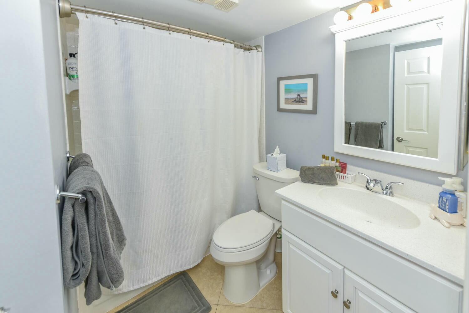 275 Palm Avenue, Unit B106 Jupiter, FL 33477 - Photo 21 of 43 a bathroom with a sink a toilet and a mirror