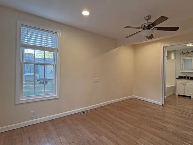 a view of empty room with wooden floor and fan