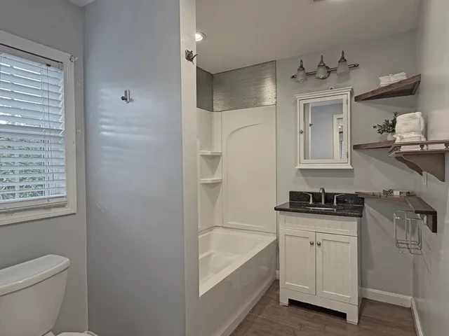 a bathroom with a granite countertop sink a toilet and bathtub