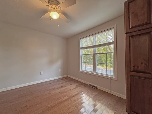 an empty room with wooden floor fan and windows