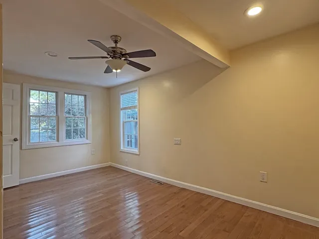 a view of an empty room with a window and wooden floor