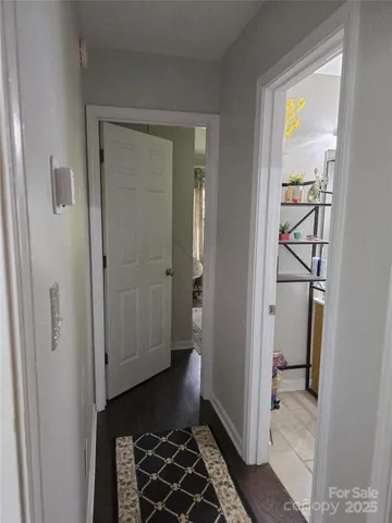 a view of a hallway with wooden floor and a bathroom