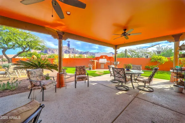 a backyard of a house with table and chairs under an umbrella