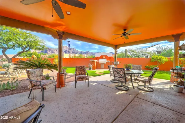 a backyard of a house with table and chairs under an umbrella