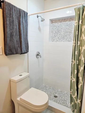 a white toilet sitting next to a shower