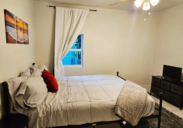 a bedroom with a bed and a flat tv screen on the dresser