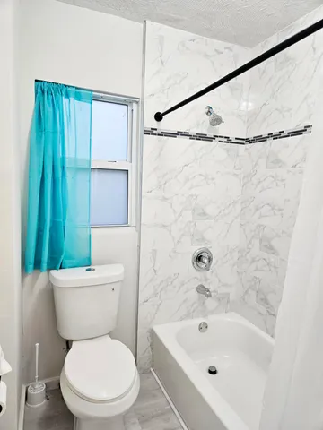 a white toilet sitting next to a bath tub shower