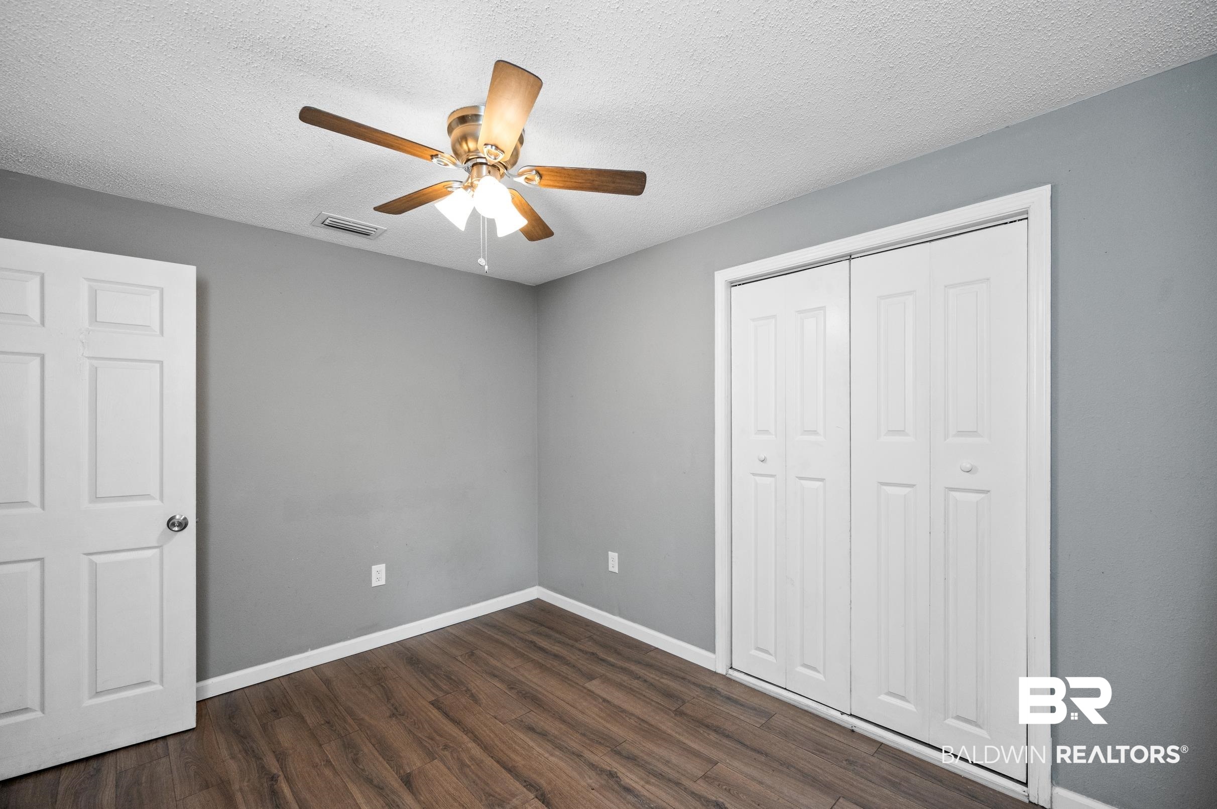 906 North Cedar Street Foley, AL 36535 - Photo 19 of 24 Unfurnished bedroom with dark wood-type flooring, a closet, a textured ceiling, and ceiling fan