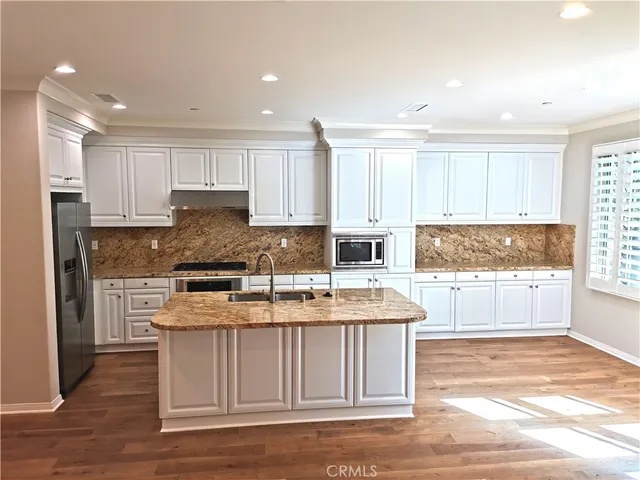 a large kitchen with stainless steel appliances granite countertop a stove a sink and a refrigerator