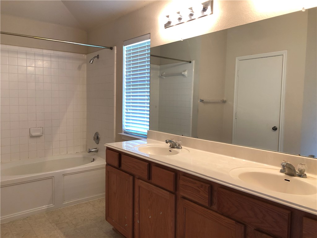 1780 Stone Rim Loop Buda, TX 78610 - Photo 10 of 19 a bathroom with a sink double vanity granite tub shower and a mirror