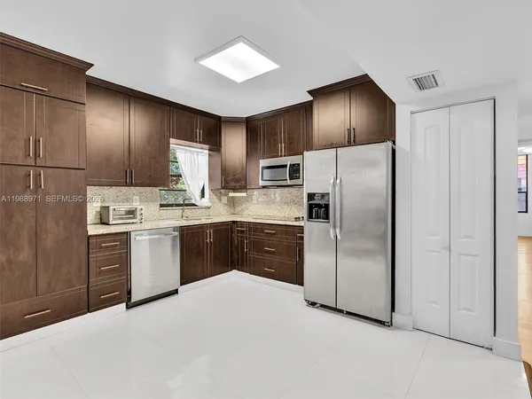 a kitchen with a refrigerator sink and wooden cabinets