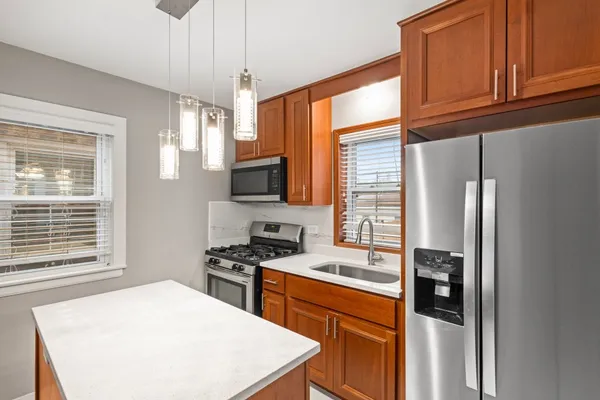 a kitchen with stainless steel appliances granite countertop a refrigerator a stove a sink and a window