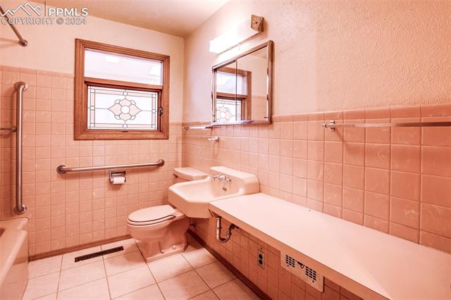 4980 Dodd Road Cascade, CO 80809 - Photo 26 of 48 Bathroom in hall featuring tile walls, tile floors, sink, and toilet