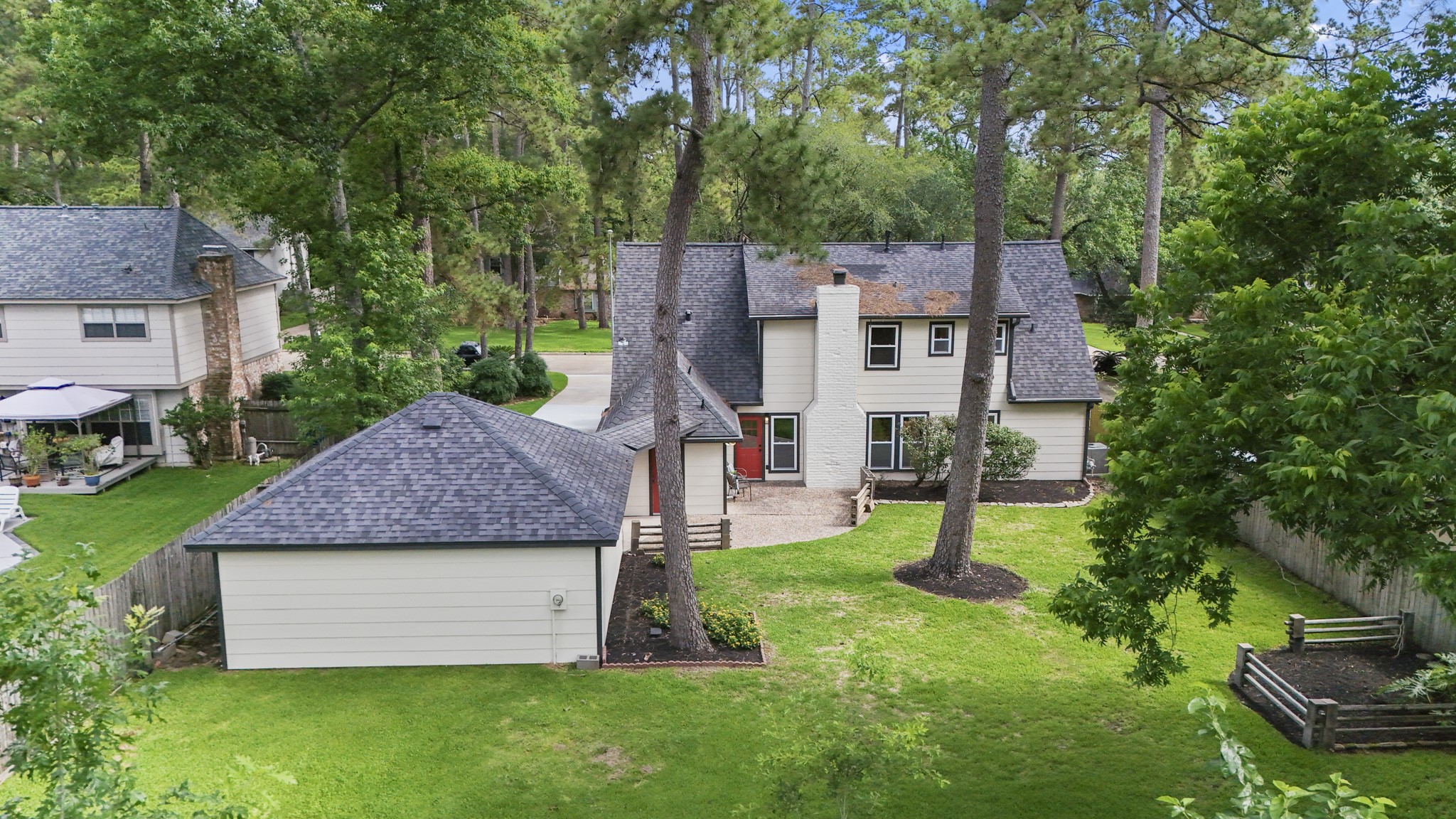 6303 Larkmount Drive Spring, TX 77389 - Photo 45 of 50 Pulling up above the backyard, this aerial gives a clear look at the home’s layout with the detached garage positioned just off the main house and connected by the covered walkway. Towering trees frame the yard, while the garage itself has been extensively rebuilt and updated, adding even more functionality to the outdoor setup.
