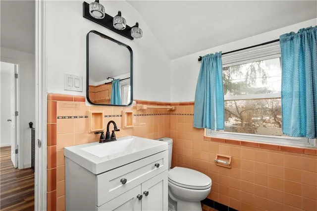 a bathroom with a toilet a sink a mirror and a window