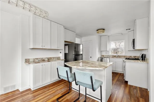 a kitchen with stainless steel appliances granite countertop a white cabinets and wooden floor