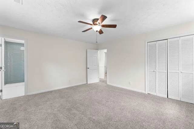 an empty room with windows and fan