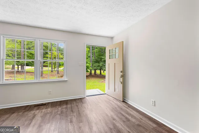 an empty room with wooden floor and windows