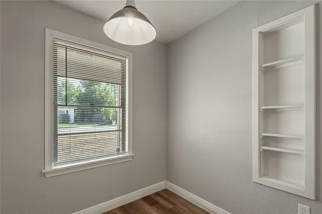 a view of an empty room with a window and wooden floor