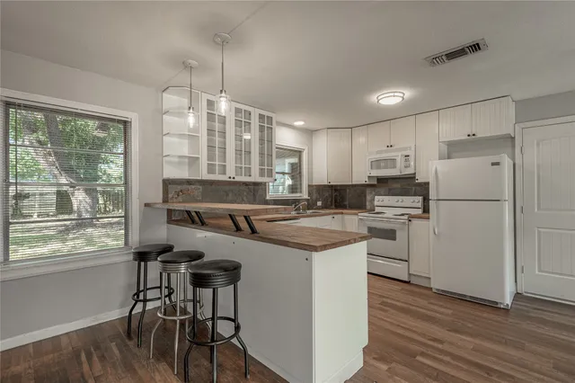 a kitchen with refrigerator a stove and wooden floor