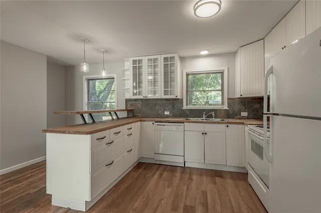 a kitchen with granite countertop white cabinets white appliances a sink and a window