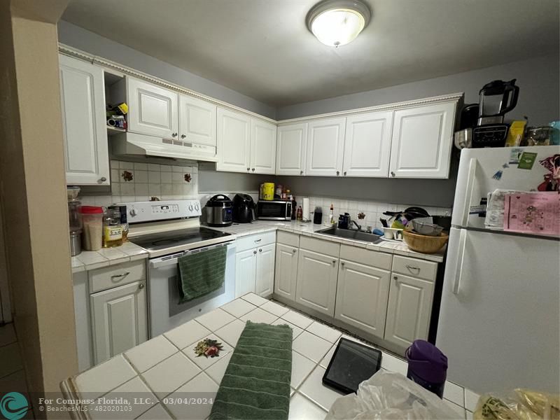 a kitchen with granite countertop a sink dishwasher stove and cabinets