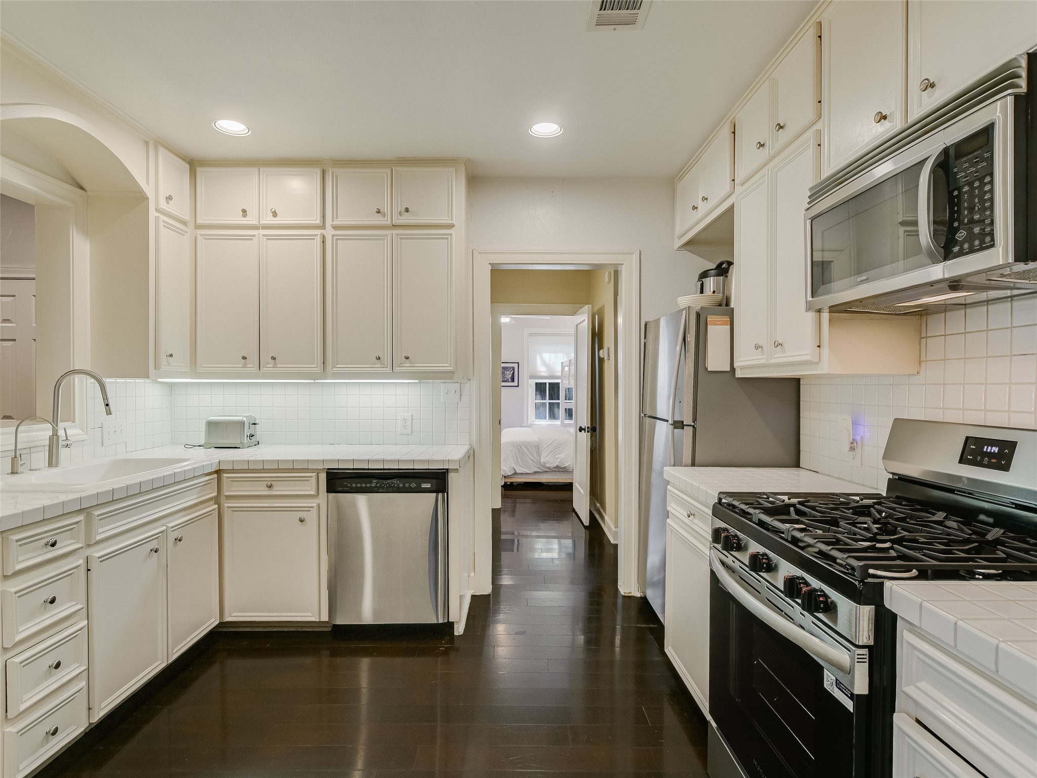 1804 Polo Road Austin, TX 78703 - Photo 5 of 19 Kitchen with stainless steel appliances, tile countertops, dark wood-type flooring, recessed lighting, and decorative backsplash