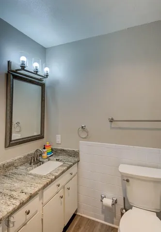 a bathroom with a granite countertop sink and a toilet