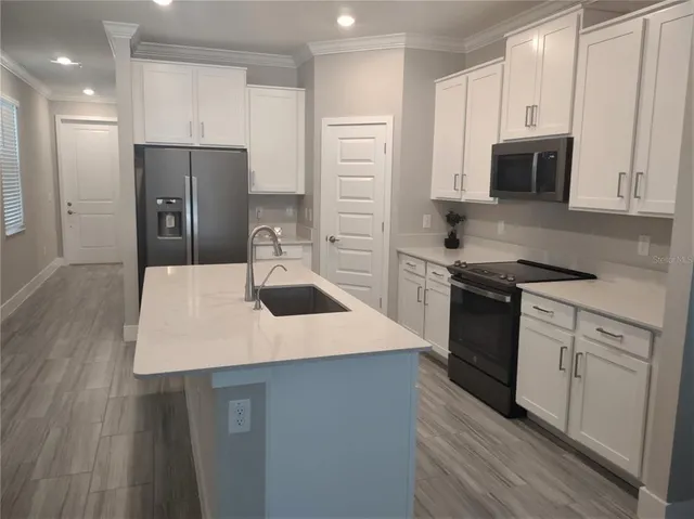 a kitchen with a sink a microwave a refrigerator and white cabinets