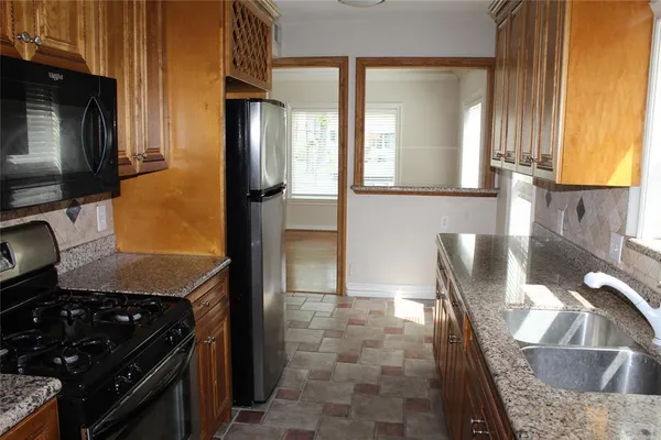 a kitchen with granite countertop a stove a sink and a refrigerator