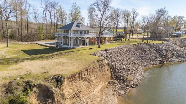 a view of a swimming pool with a patio and a yard with trees