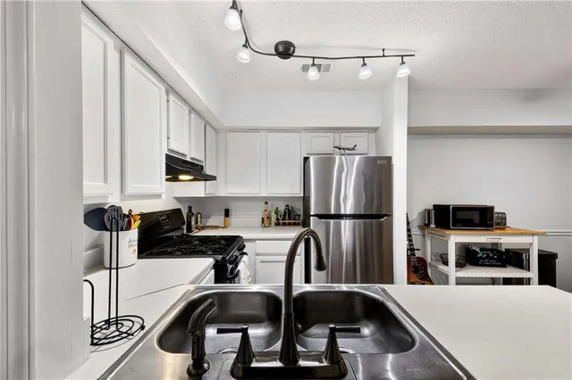 a kitchen with a refrigerator a sink a stove and white cabinets