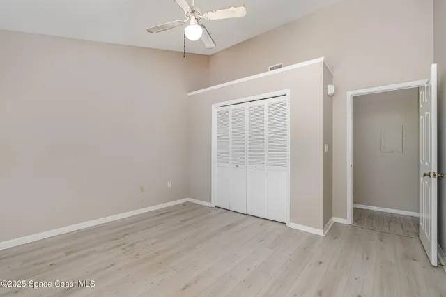 an empty room with wooden floor and fan