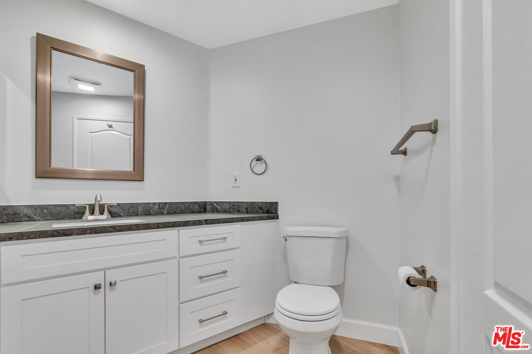4477 Woodman Avenue, Unit 207 Sherman Oaks, CA 91423 - Photo 25 of 34 a bathroom with a granite countertop toilet sink and mirror